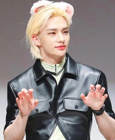 a man with blonde hair wearing a black leather jacket and cat ears on his head