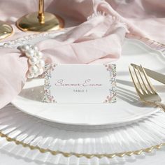 a table setting with place cards and silverware on it, including a gold fork