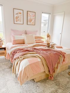 a bed with pink and white comforters in a bedroom next to a window,