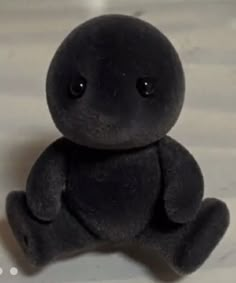 a small black teddy bear sitting on top of a table