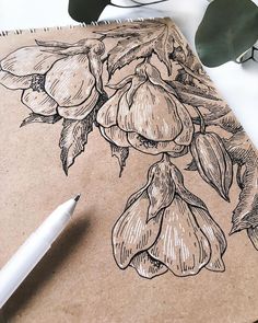 a drawing of flowers on a piece of brown paper next to a pen and plant