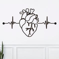 a metal heart on a white wall with a stethoscope