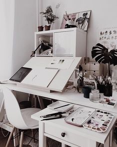 a white desk topped with a laptop computer and lots of office supplies next to a window