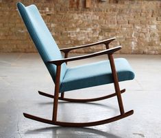 a blue rocking chair sitting on top of a white floor next to a brick wall