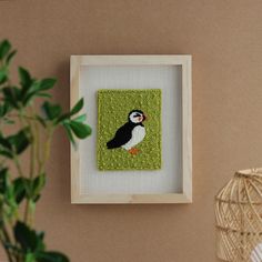 there is a framed picture with a small bird on it and a plant in the corner