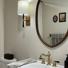 a bathroom sink sitting under a mirror next to a white toilet covered in a towel