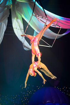 two acrobats performing aerial tricks on stage