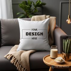 a white pillow sitting on top of a couch next to a cup and potted plant