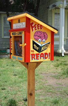 a yellow and red mailbox with a book box on it's side that reads feed the mind to read