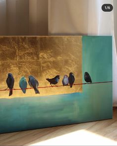 four birds sitting on a wire in front of a gold and teal wall painting