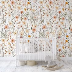 a white crib in front of a floral wallpaper