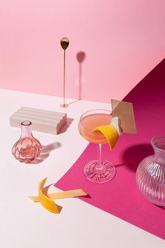 two pink vases and one yellow glass on a white table