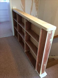 an unfinished bookcase in the corner of a room with carpeted floor and walls