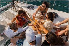 a group of people sitting on the back of a boat drinking wine and having drinks