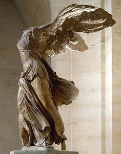 an angel statue with its wings spread out in front of a wall and columns on either side