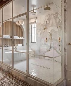 an elegant bathroom with marble floors and walls, along with glass doors that open up to the shower area