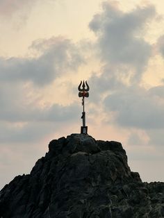 a wind vane on top of a rock formation