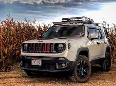 a white jeep parked in front of a corn field