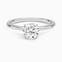 a white gold ring with a round brilliant cut diamond in the center, on a plain surface