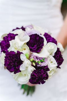 a bride holding a purple and white bouquet