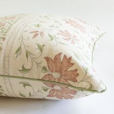 a close up of a flowered pillow on a white surface with green trimming