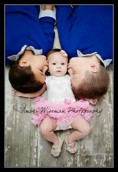 three babies are laying on the floor with their heads touching each other's noses