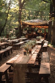 a long wooden table sitting in the middle of a forest filled with lots of lights