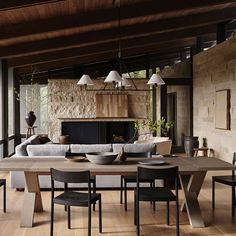 a dining room table and chairs in front of a stone wall with an open fireplace