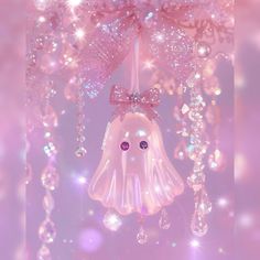 a pink and white bell ornament hanging from a chandelier with crystal beads