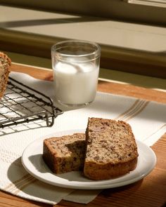 two slices of banana bread on a plate next to a glass of milk and cooling rack