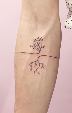 a small tree tattoo on the left leg with roots growing out of it's trunk