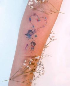 a woman's arm with flowers and fairy tattoos on it