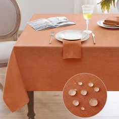 an orange table cloth with white plates and silverware on it next to a vase