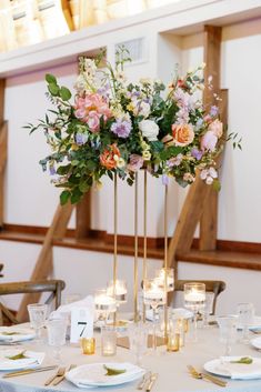 a tall centerpiece with flowers and candles on a table