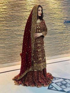 a woman in a red and gold bridal gown standing next to a large wall