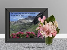 a vase filled with pink flowers sitting next to a framed photo on top of a wall