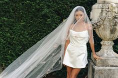 a woman standing next to a statue wearing a wedding veil