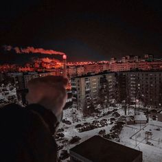 a person taking a photo at night with their cell phone in front of the city