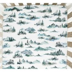 a baby crib with mountains and trees on it