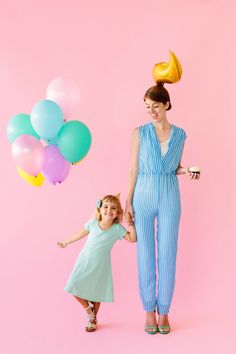 a mother and daughter holding hands with balloons floating in the air behind them on a pink background