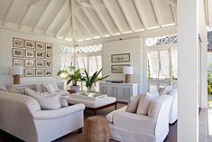 a living room filled with white furniture and lots of windows