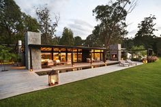 a house that is sitting in the grass with lights on it's porch and patio