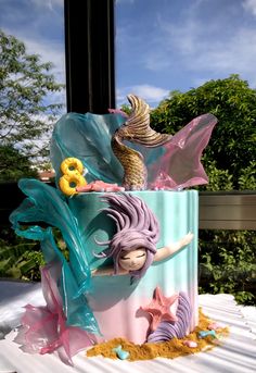 there is a cake decorated with mermaids and seashells