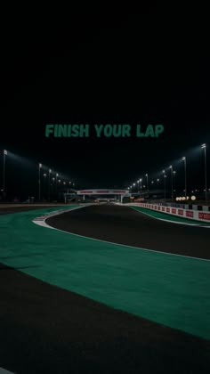 an empty race track at night with the words finish your lap on it's side