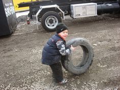 a young boy holding a tire in front of a truck