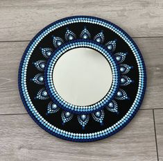 a blue and black circular mirror sitting on top of a wooden floor