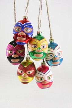 six christmas ornaments with different colored masks hanging from strings in the shape of people's faces