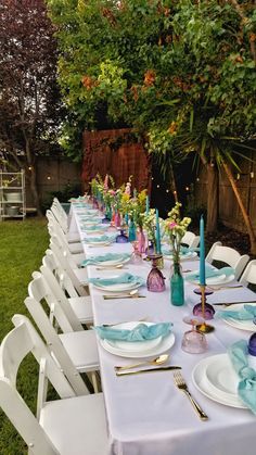 a long table is set with blue and white plates, silverware, and napkins