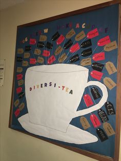 a large tea cup is hanging on the wall next to a bulletin board with words and magnets