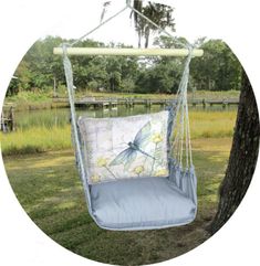 a blue swing chair hanging from a tree with a butterfly pillow on it's back